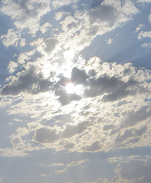 خورشید پشت ابرهای پاره‌پاره پنهان شده و نورش از لابه‌لای آن‌ها در آسمان روستا پخش شده است.